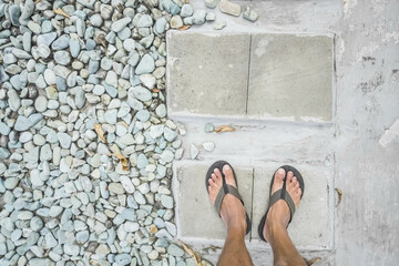 High Angle View of Low Section of man with sandals standing on rocky ground. Illustration for Single, freedom, simple life, solitude, confused decision making, solo traveling, starting a business.