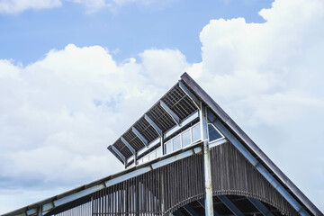 Obraz premium The upper part of the roof of a modern building using clay, wood, steel and glass roofing materials with sky background. Concept for modern architecture, urban home, hotel, cafe, restaurant design.