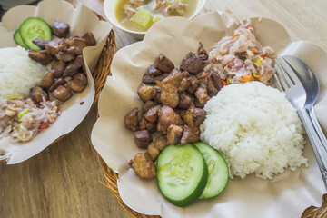 Fried pork served with white rice, sambal matah, cucumber. Balinese mixed rice or nasi campur. Bali authentic delicious food.