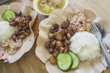 Fried pork served with white rice, sambal matah, cucumber. Balinese mixed rice or nasi campur. Bali authentic delicious food.