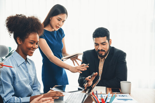 Multiracial analyst team use BI dashboard data to analyze financial report on meeting table. Group of diverse business people utilize data analysis by FIntech for business marketing decision. Concord
