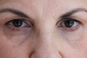 Senior woman face with dark brown eyes and wrinkles