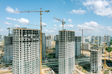 new multistory apartment buildings under construction with cranes on construction site. aerial drone photo.