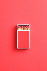 red matchstick in red matchbox on red paper background with copy space