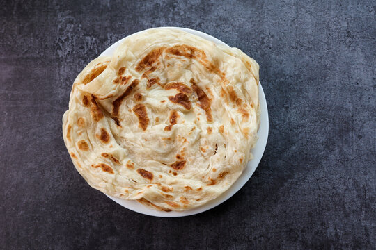 Kerala parathas porotta roti parotta barotta naan layered flatbread made from maida or whole wheat flour. Eat with spicy Asian chicken or beef or egg curry gravy. breakfast dish. Indian food.