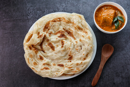 Fish curry with Kerala parathas porotta roti parotta barotta naan layered flatbread made from maida whole wheat flour. Eat with spicy Asian chicken beef egg curry gravy. breakfast dish. Indian food.