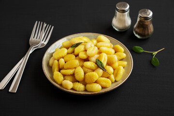 Homemade Easy Potato Gnocchi on a Plate on a black background, side view.