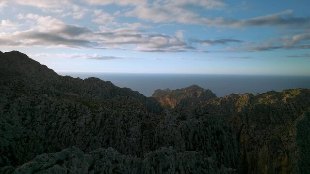 Sa Calobra Port de Soller mountains, Palma de Mallorca. Green slopes and hills, blue seaside sky sunset horizon. Scenic Majorca Island mountain ridge peak nature aerial drone footage. Cinematic 4K UHD