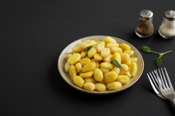 Homemade Easy Potato Gnocchi on a Plate on a black background, side view. Space for text.