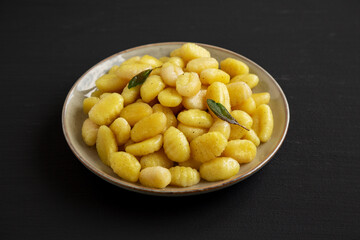 Homemade Easy Potato Gnocchi on a Plate on a black background, side view.