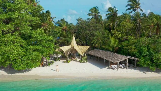 Aerial view on Woman walking on the white sandy beach in Bora Bora, French Polinesia. Tourist vacation and lifestyle.