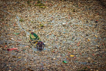 People collect trash that can be recycled and traded from the sea of garbage in the Citarum River,...
