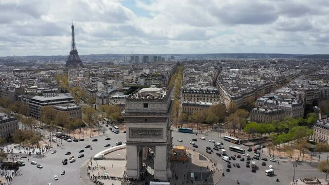 Aerial view of Arc de Triomphe with people overlooking Paris from the top terrace. Eifel Tower in background, France