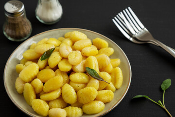 Homemade Easy Potato Gnocchi on a Plate on a black background, side view.