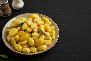 Homemade Easy Potato Gnocchi on a Plate on a black background, side view. Copy space.
