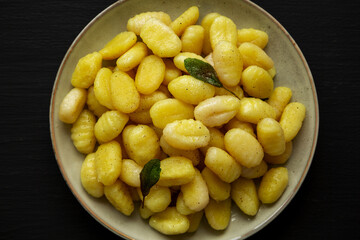 Homemade Easy Potato Gnocchi on a Plate on a black background, top view. Flat lay, overhead, from above. Close-up.