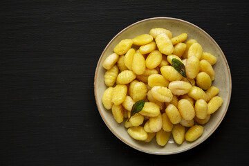 Homemade Easy Potato Gnocchi on a Plate on a black background, top view. Flat lay, overhead, from above. Space for text.