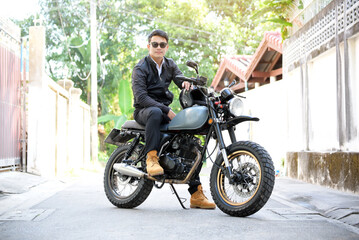 Obraz na płótnie Canvas Asian man motorbike in black leather jacket travel rider trip. Handsome Men wear sunglass outdoor lifestyle freedom rider. Men trendy hipster cool person. Young asian man hobby ride with motor bike