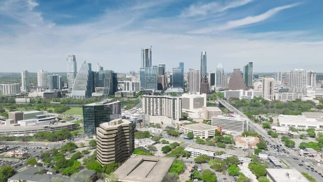 Drone flying above green suburban area with scenic business office buildings in downtown Austin cityscape on sunny summer day Texas 4K aerial USA. Austin skyscraper buildings skyline video blue sky