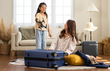 Portrait of happy love asian family mother with little asian girl traveler packing stuff and outfit clothes in suitcases travel bag luggage for summer holiday weekend tourist vacation trip at home