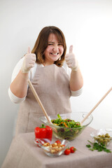 adult European woman shows a class preparing food on a white background beige tablecloth salad proper nutrition positive