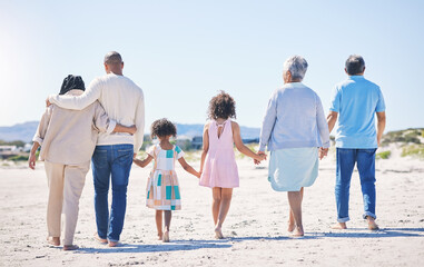 Holding hands, back and big family at the beach for holiday, walking and summer weekend by the ocean. Affection, support and parents, children and grandparents on a walk by the seaside for bonding