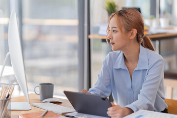 Happy young businesswoman Asian siting on the chairs cheerful demeanor raise holding coffee cup smiling looking laptop screen. Making opportunities female working successful in the office.