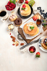 Pancakes with fresh fruits, donuts and coffee on a white background.