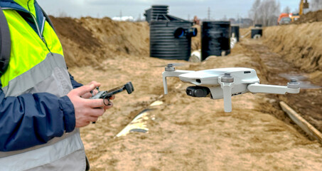 a surveyor engineer with a quadcopter on a construction site