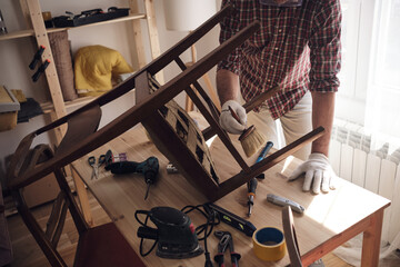 Man working in a small home workshop for furniture repairing and restoration.