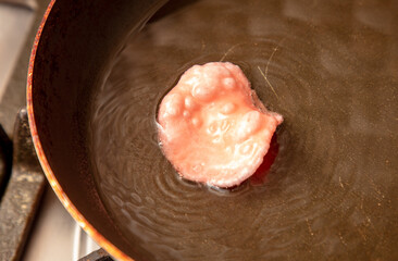 Red chips are fried in oil in a frying pan