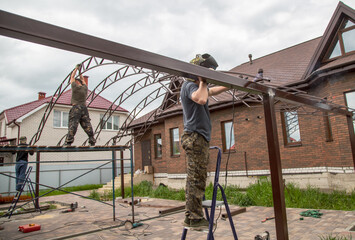 Fototapeta na wymiar The worker installs the metal on the canopy.