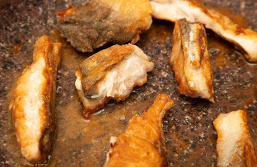 The fish is fried in a frying pan in oil. Close-up.