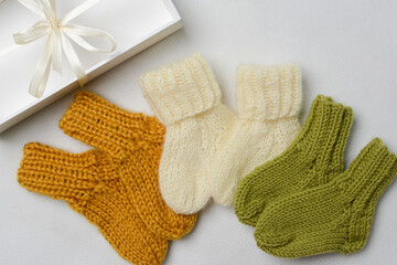 Small baby socks, made of cotton yarn, on white wooden background