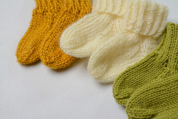 Fototapeta na wymiar Small baby socks, made of cotton yarn, on white wooden background