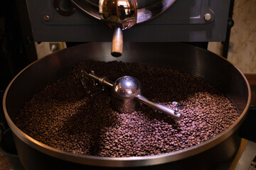 process of preparing, roasting fresh raw coffee beans grain in coffee roaster professional machine. soft focus.