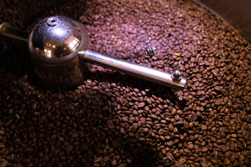 process of preparing, roasting fresh raw coffee beans grain in coffee roaster professional machine. soft focus. close up