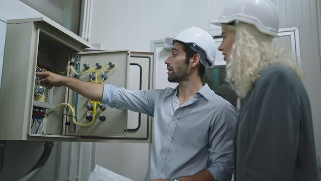 Professional caucasian male engineer discuss and explain usage electricity production controller of the factory to caucasian woman warehouse manager