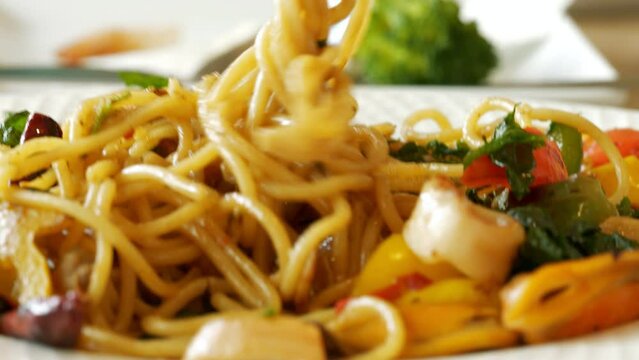 4K footage close-up front view, Use a fork to scoop the spaghetti on a white plate on the restaurant table.
