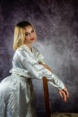 young slender blonde woman in a stylish dressing gown isolated on a beautiful background.