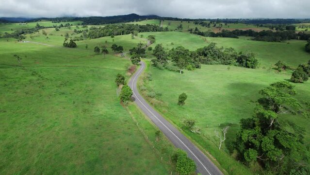 drone shot over a road with a campervan driving in the distance in Queensland, Australia countryside