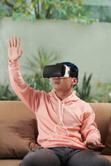 Obraz premium Young man in pink hoodie playing videogame in VR headset