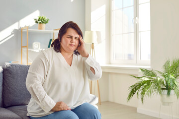 Overweight young woman suffering from headache, migraine or dizziness. Exhausted plus size, plump...