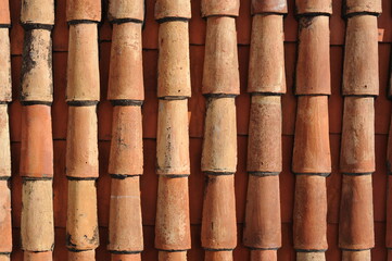 Red and orange roof tiles texture pattern on roof of an old historical building