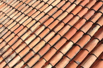 Red and orange roof tiles texture pattern on roof of an old historical building