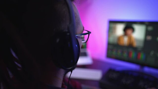 Young man in glasses working on video editing on computer doing montage and color correction. Professional man hand making edits on a special panel. Concept of creating video content.