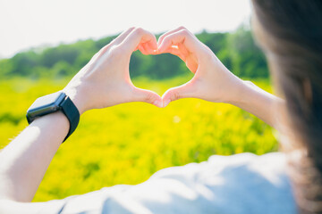 Hands of woman traveling and gesturing heart shaped of forest background with green trees.