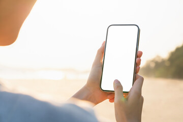 Hand holding smartphone on the beach, mobile mockup of blank screen, Take your screen to put on advertising. Summer vacation concept.