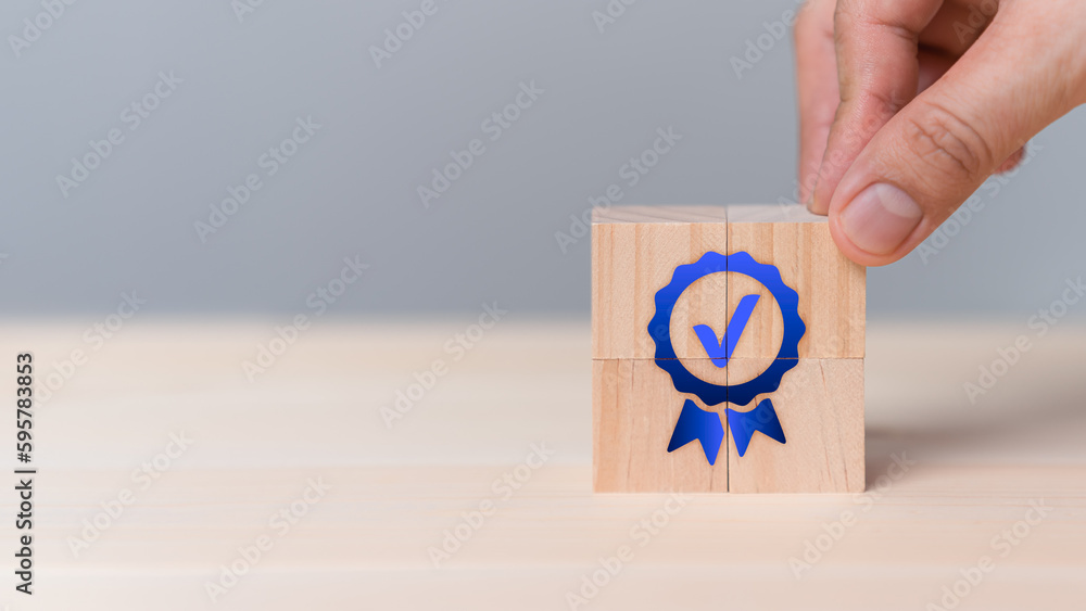 Poster hand put a quality guarantee sign on wooden cube on table. service quality assurance, standards, iso