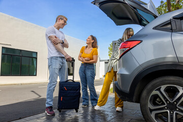 Caucasian family is fitting their luggage in the trunk after renting a car at the airport terminal...